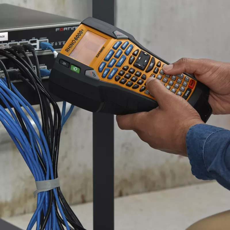 DYMO Rhino 6000+ pramoninis etikečių spausdintuvas | Prie kompiuterio jungiamas etikečių spausdintuvas su kietu nešiojimo dėklu | Sudėtyje yra 1 vinilo juostos kasetė, 1 lanksti nailono juostos kasetė ir įkraunama ličio jonų baterija